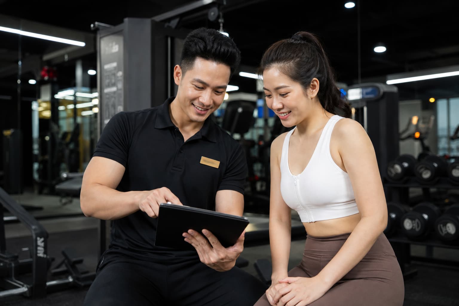 PT và học viên cùng xem lại kế hoạch tập luyện cá nhân hóa trên máy tính bảng